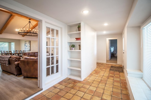 hallway with a wealth of natural light, a notable chandelier, and built in shelves