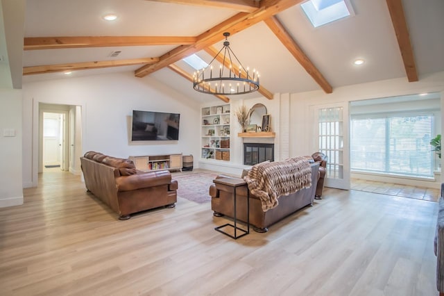 living room with built in features, light hardwood / wood-style flooring, lofted ceiling with skylight, and a chandelier