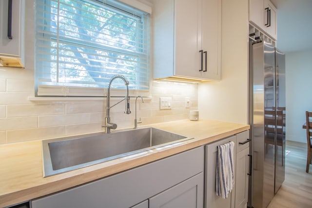 kitchen featuring sink, backsplash, stainless steel fridge, and wooden counters