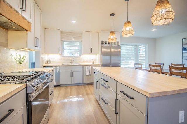 kitchen featuring premium range hood, wood counters, appliances with stainless steel finishes, and sink