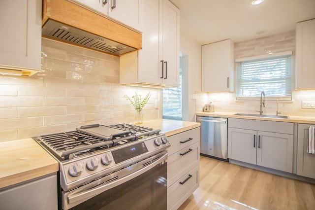 kitchen featuring premium range hood, appliances with stainless steel finishes, sink, and white cabinets