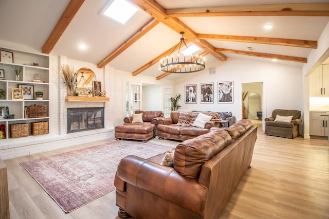 living room featuring beam ceiling, light wood-type flooring, a fireplace, and a chandelier