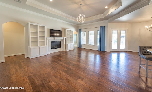 4003 124th St, Lubbock, TX 79423 - unfurnished living room with a chandelier, a tray ceiling, dark wood-type flooring, arched walkways, and ornamental molding