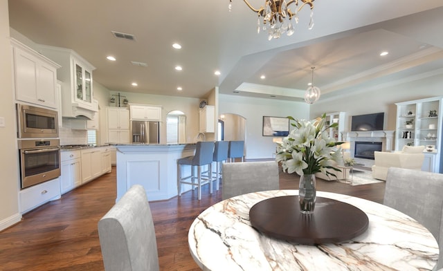 4003 124th St, Lubbock, TX 79423 - dining room featuring a chandelier, arched walkways, dark wood-type flooring, ornamental molding, and a tray ceiling
