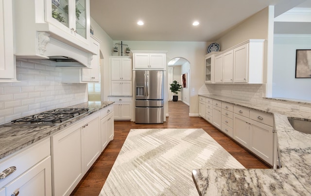 4003 124th St, Lubbock, TX 79423 - kitchen with stainless steel appliances, arched walkways, white cabinets, light stone counters, and glass insert cabinets
