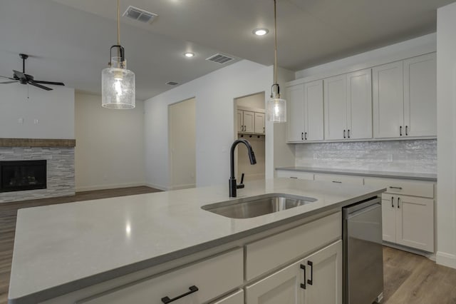 kitchen featuring an island with sink, sink, hanging light fixtures, and white cabinets