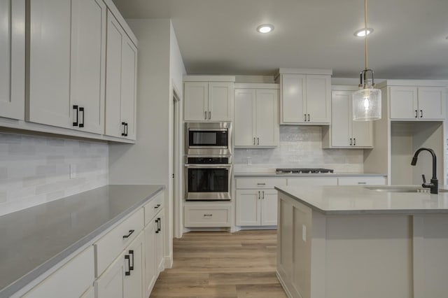 kitchen featuring appliances with stainless steel finishes, decorative light fixtures, sink, and white cabinets