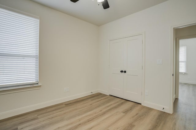 unfurnished bedroom with ceiling fan, a closet, and light wood-type flooring