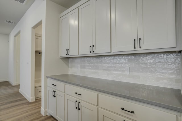 kitchen with white cabinetry, light wood-type flooring, and decorative backsplash