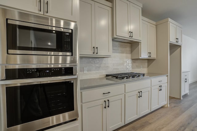 kitchen featuring white cabinetry, appliances with stainless steel finishes, tasteful backsplash, and light wood-type flooring