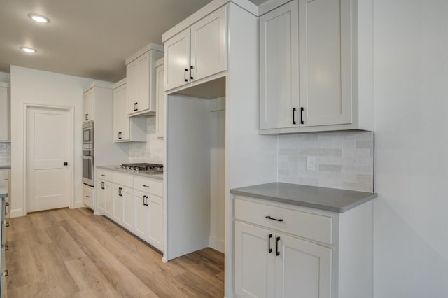 kitchen with tasteful backsplash, white cabinets, and light wood-type flooring