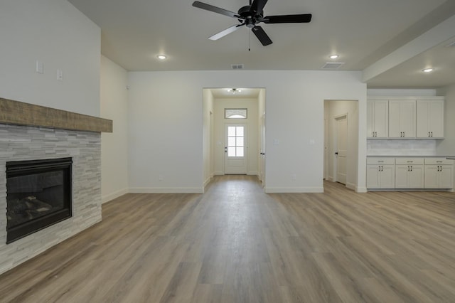 unfurnished living room with ceiling fan, a tile fireplace, and light hardwood / wood-style flooring