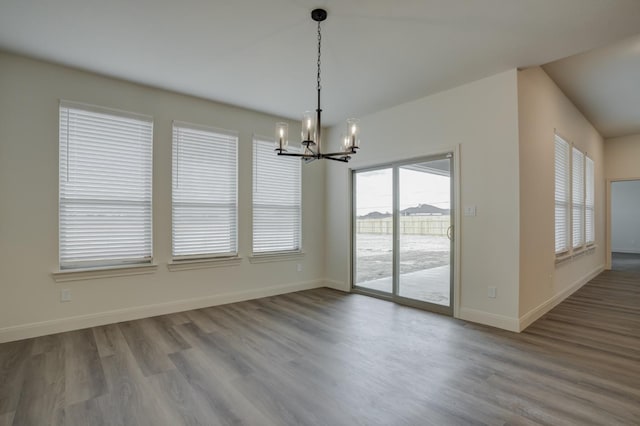 unfurnished dining area with hardwood / wood-style floors and a chandelier