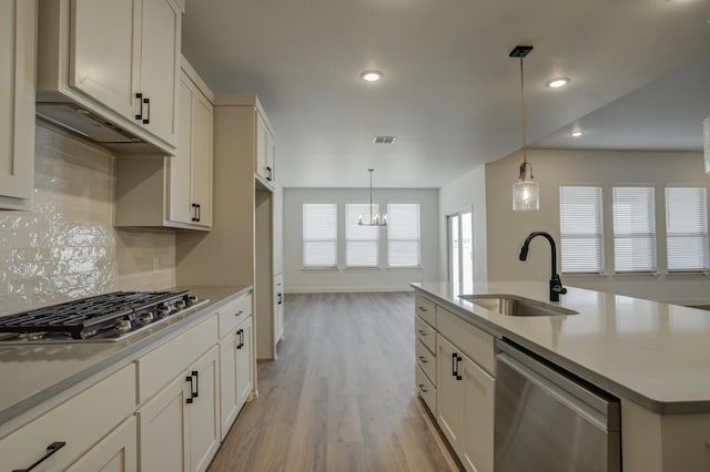 kitchen featuring sink, hanging light fixtures, light wood-type flooring, an island with sink, and stainless steel appliances