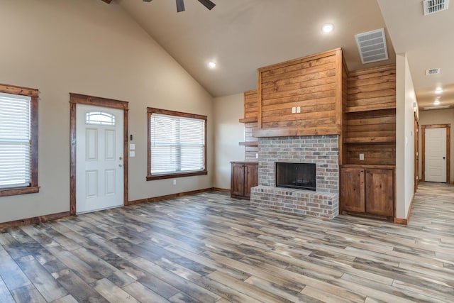 unfurnished living room with a wealth of natural light, a brick fireplace, and visible vents