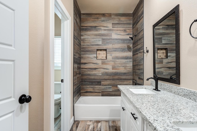 full bathroom with double vanity, toilet, a sink, shower / tub combination, and wood finished floors