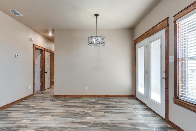 empty room featuring baseboards, a chandelier, and a wealth of natural light