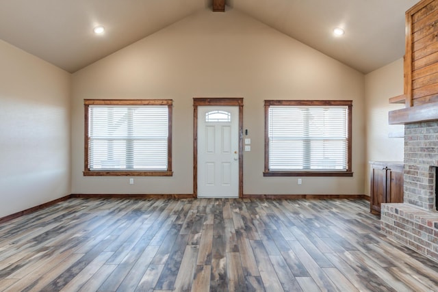 interior space with a brick fireplace, plenty of natural light, baseboards, and wood finished floors