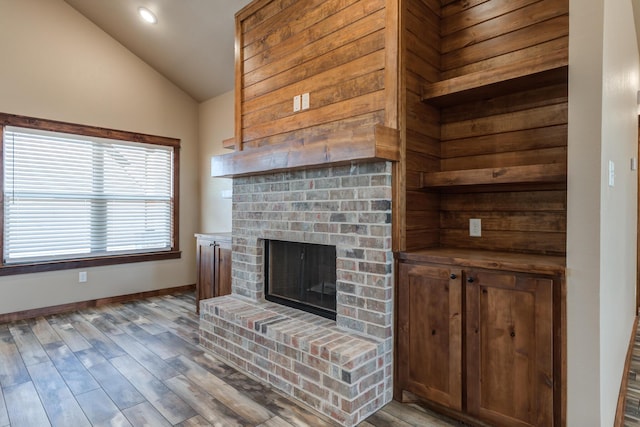 living room featuring vaulted ceiling, a fireplace, wood finished floors, and baseboards