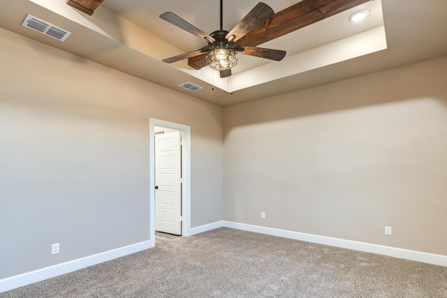 unfurnished room with baseboards, a tray ceiling, visible vents, and light colored carpet