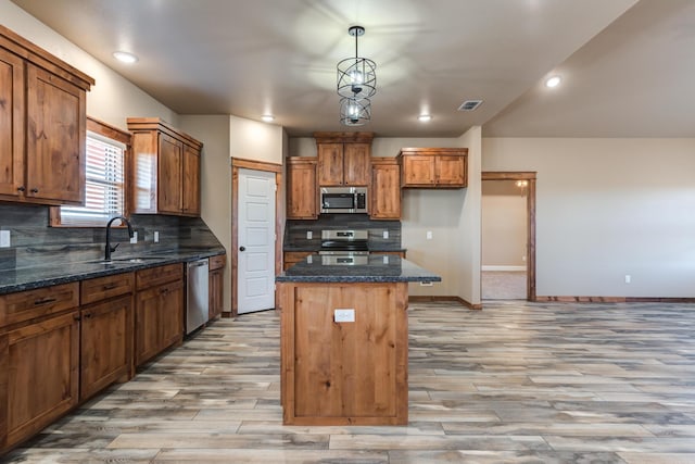 kitchen with a sink, visible vents, a center island, appliances with stainless steel finishes, and brown cabinets