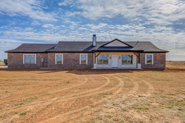 view of front of house with brick siding, a chimney, and a front yard