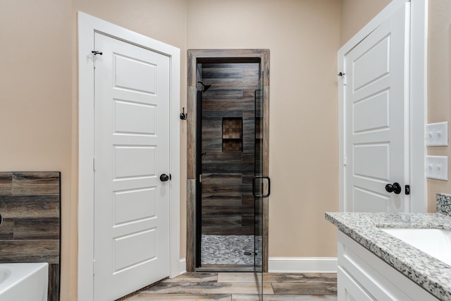 full bathroom featuring a garden tub, vanity, a shower stall, wood finished floors, and baseboards