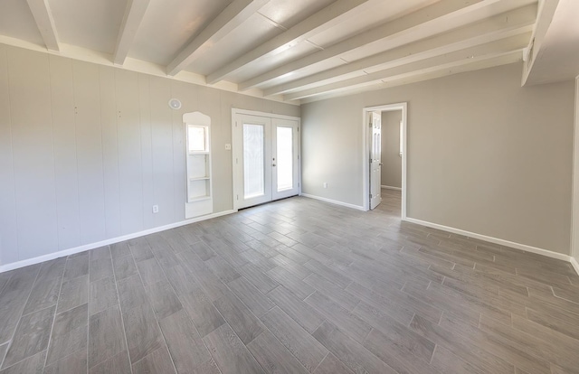 empty room with beam ceiling, french doors, and hardwood / wood-style flooring