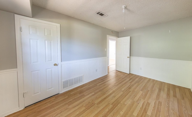 unfurnished bedroom featuring a textured ceiling and light hardwood / wood-style floors