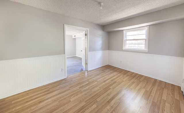 spare room with a textured ceiling and light wood-type flooring