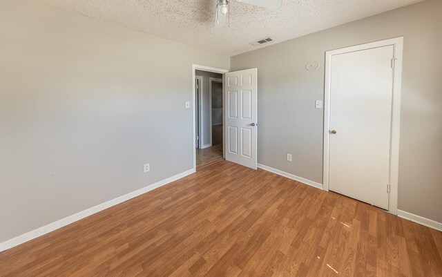 unfurnished bedroom featuring ceiling fan, a textured ceiling, and light hardwood / wood-style flooring