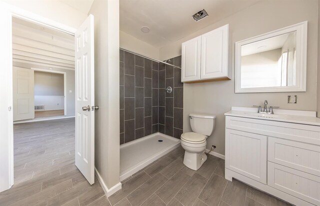 bathroom featuring vanity, toilet, and tiled shower