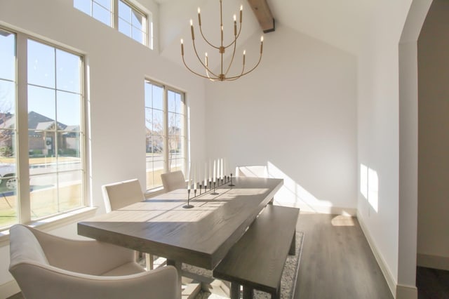 dining area with a wealth of natural light, beamed ceiling, light hardwood / wood-style floors, and a chandelier