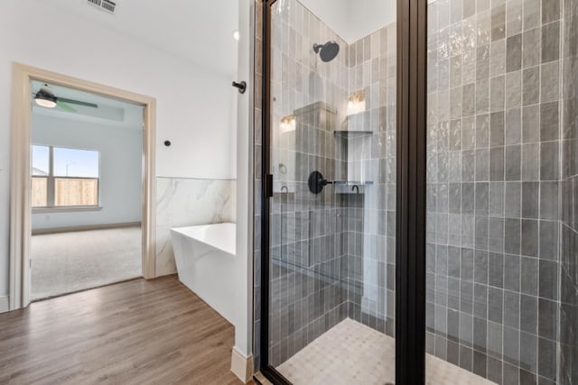 bathroom featuring tile walls, wood-type flooring, and shower with separate bathtub