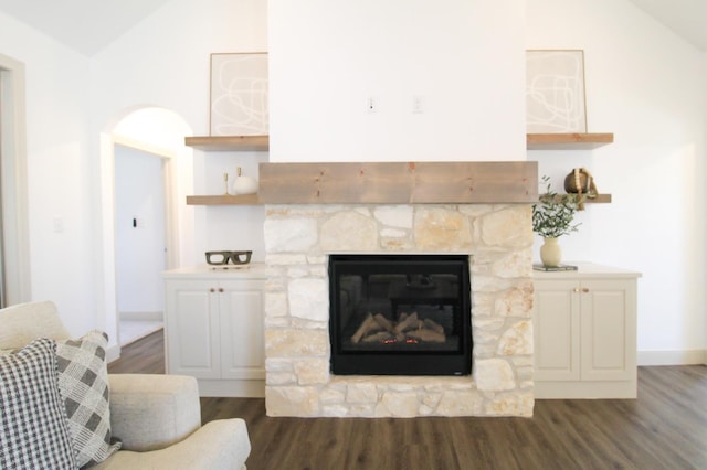 living room featuring vaulted ceiling, dark wood-type flooring, and a fireplace