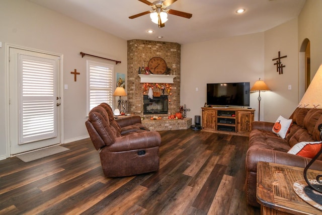 living room featuring ceiling fan, a brick fireplace, and dark hardwood / wood-style flooring