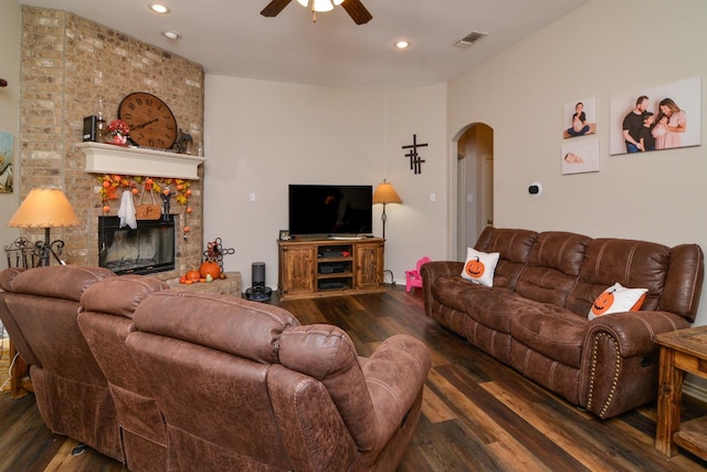 living room with dark wood-type flooring, ceiling fan, and a fireplace