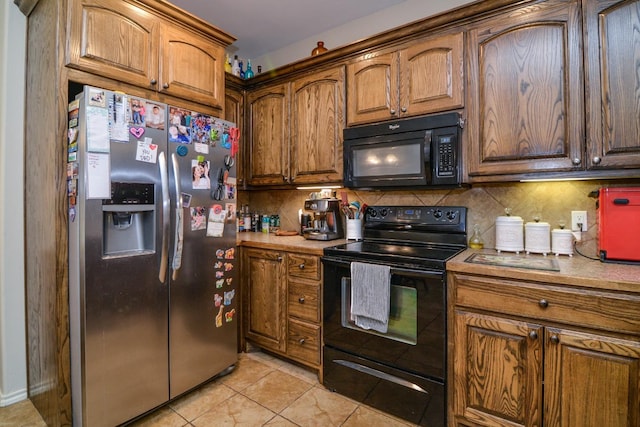 kitchen with light tile patterned floors, backsplash, and black appliances