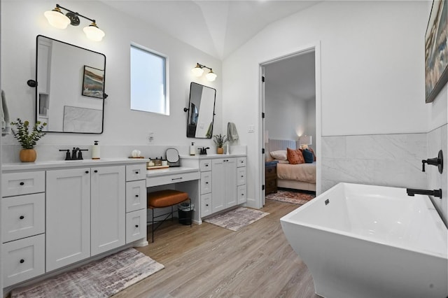 bathroom with vanity, a bath, and wood-type flooring