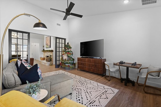 living room featuring a high ceiling, hardwood / wood-style floors, and ceiling fan