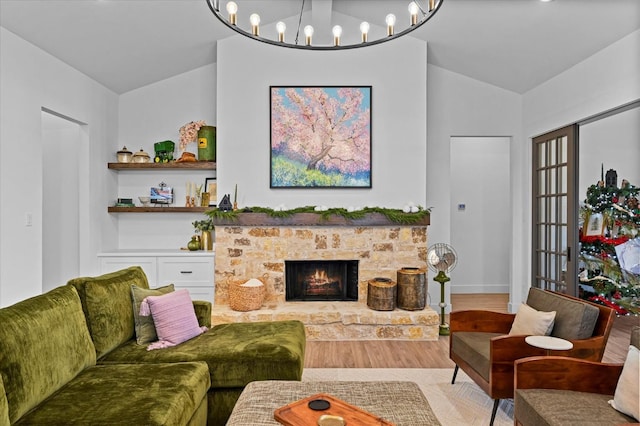 living room with lofted ceiling, a notable chandelier, a fireplace, and light wood-type flooring