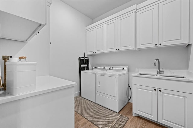 laundry room with cabinets, washer and clothes dryer, sink, and light wood-type flooring