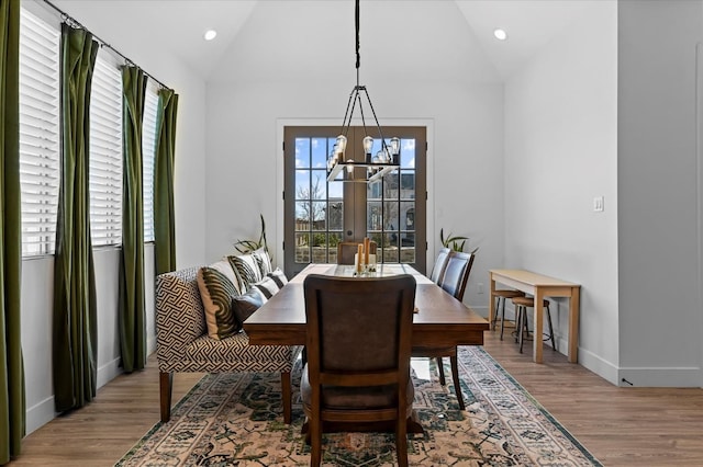 dining room featuring vaulted ceiling, a notable chandelier, and light hardwood / wood-style floors