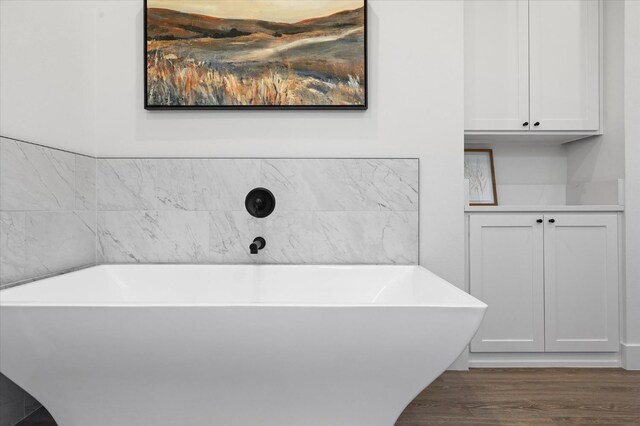 bathroom featuring hardwood / wood-style flooring and a tub to relax in