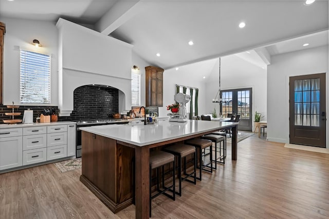 kitchen with light hardwood / wood-style flooring, a breakfast bar area, gas stove, a kitchen island, and french doors