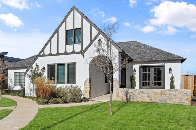 tudor-style house featuring a front lawn and french doors