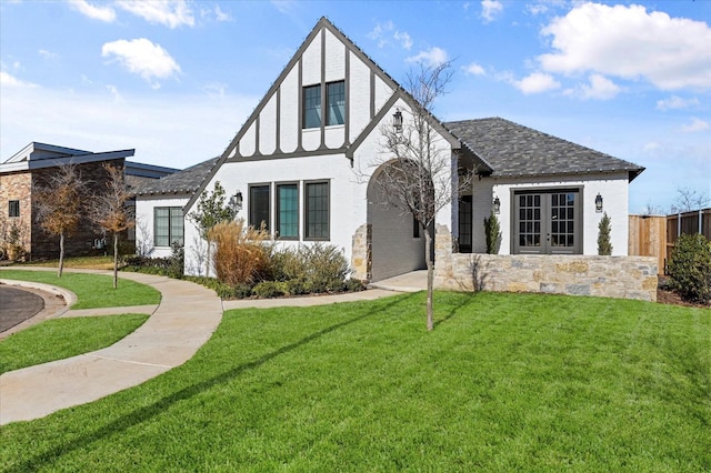 tudor-style house featuring french doors and a front yard