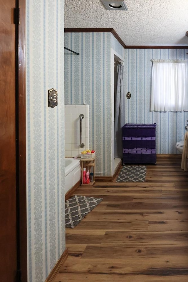 bathroom featuring hardwood / wood-style flooring, crown molding, a textured ceiling, and toilet