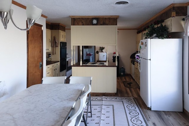 kitchen with wood-type flooring, white fridge, a textured ceiling, and double oven