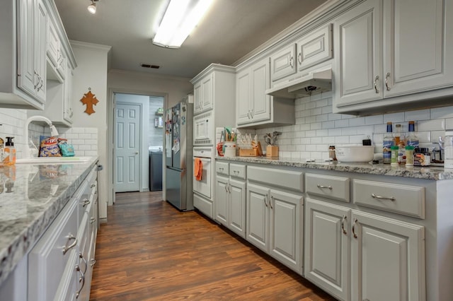 kitchen with light stone counters, dark hardwood / wood-style floors, crown molding, and stainless steel refrigerator